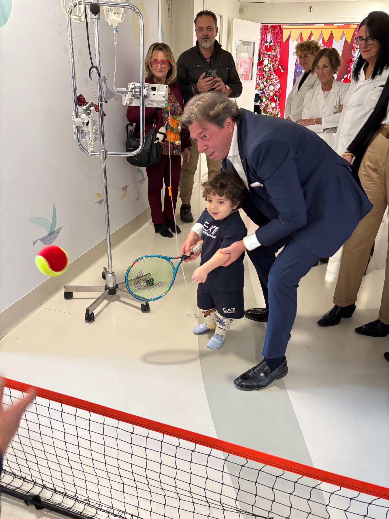Il Prof. Giorgio Meneschincheri, Presidente e Fondatore di Tennis & Friends, mentre aiuta il piccolo Diego, 4 anni, nei suoi primi colpi con la racchetta