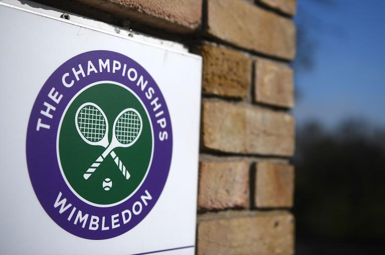 Un addetto al lavoro con la mascherina all'interno dei cancelli di Wimbledon di fronte al Centre Court